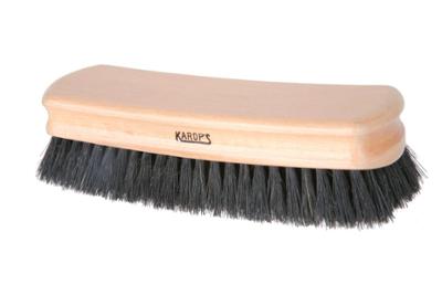 Brosse à habit cintrée KAROP'S en bois verni, à soies noires, pour un dépoussiérage efficace des vêtements.